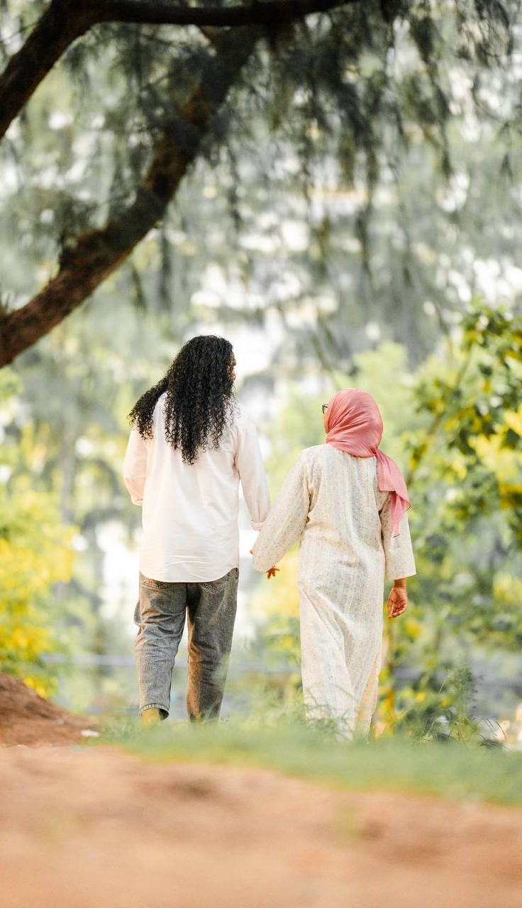 Wasiu and Shafga walking hand in hand under the trees